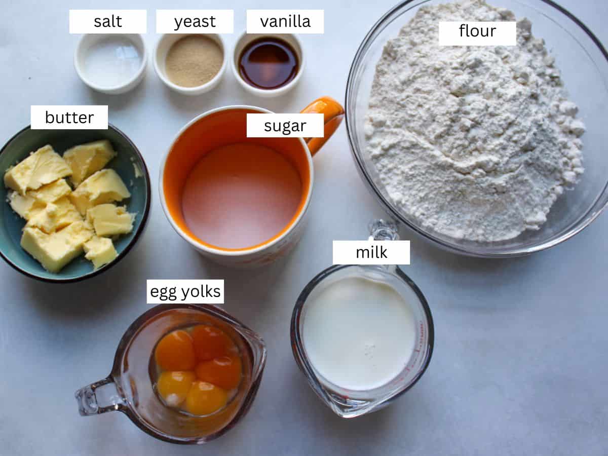 All measured ingredients for making Paska including flour, egg yolks, sugar, milk, butter, yeast, vanilla extract and salt. 