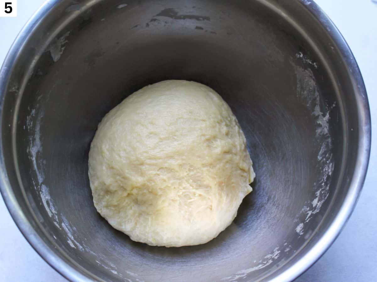 Kneaded dough formed into a ball in a large bowl. 