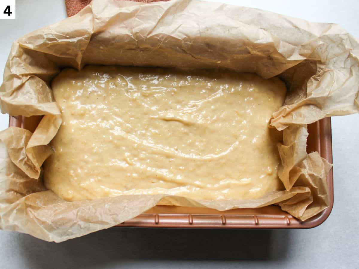 Banana bread batter poured into the load pan lined with parchment paper.