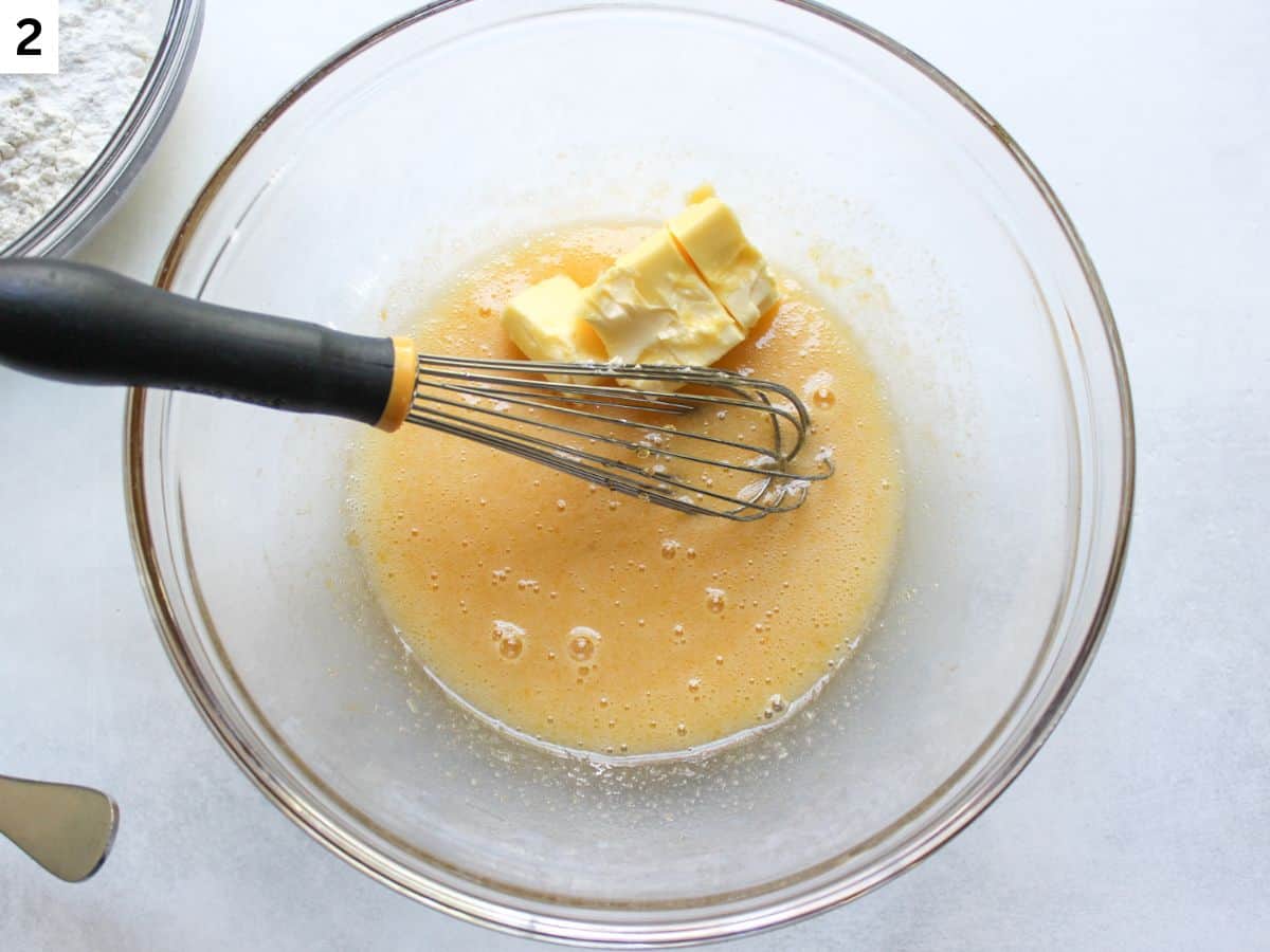 Softened butter added to the whisked ingredients in a glass bowl. 