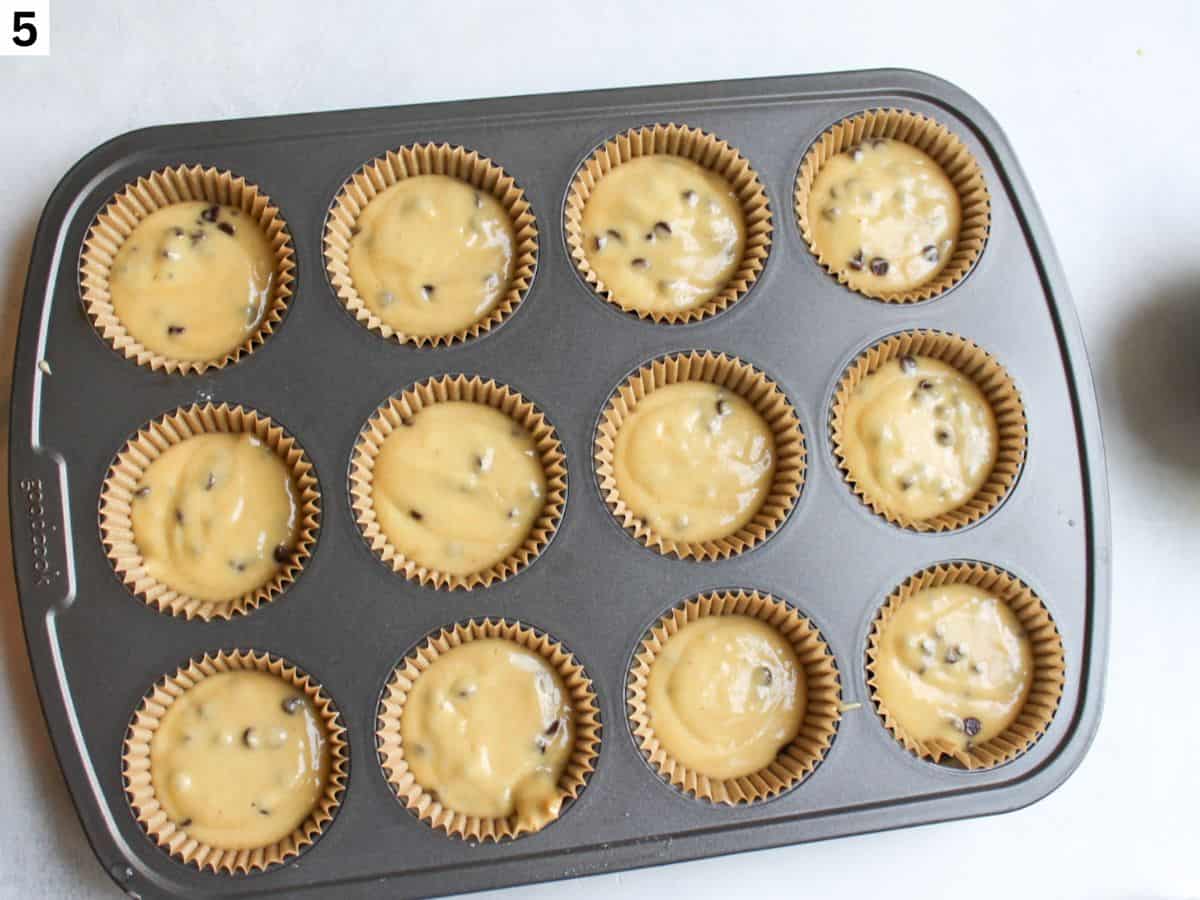 Honey muffin batter divided between 12 muffin cups lined with parchment paper liners. 