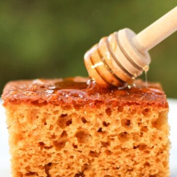 Dripping honey with honey stick over the slice of honey cake.