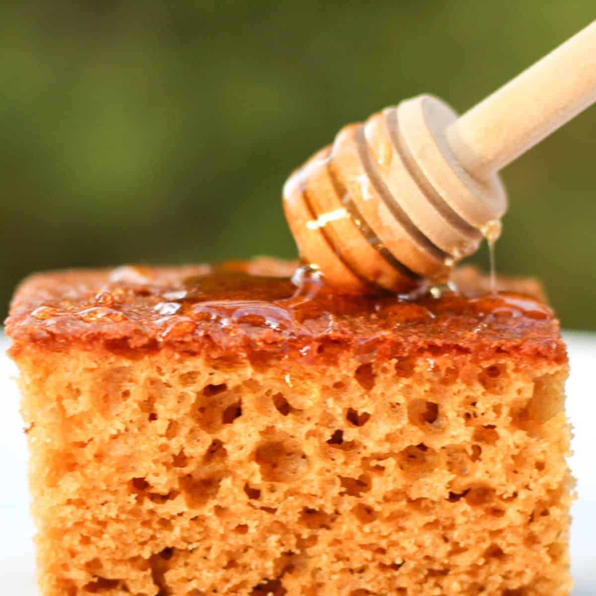 Dripping honey with honey stick over the slice of honey cake.