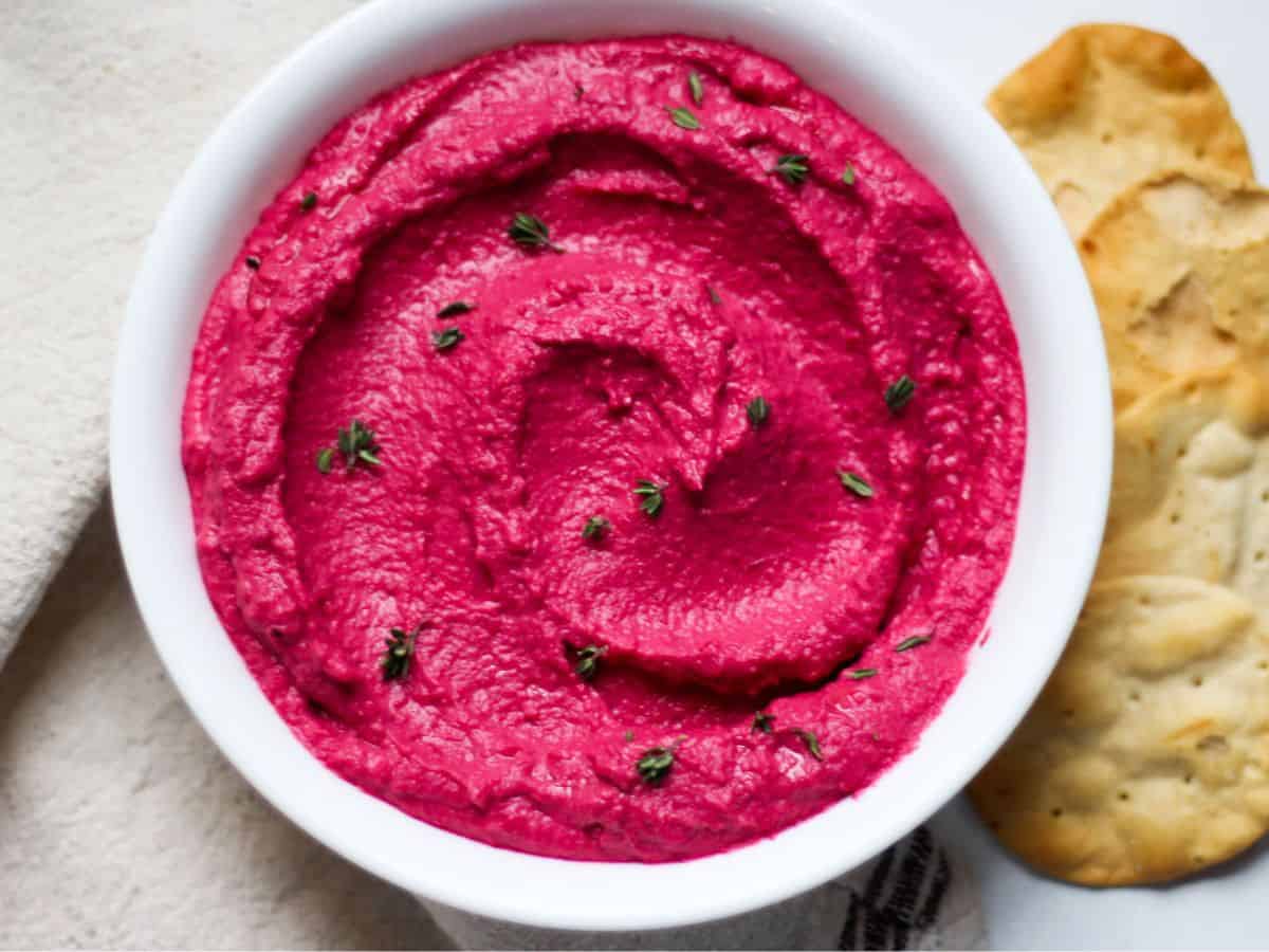 Creamy beetroot hummus in a white bowl. 