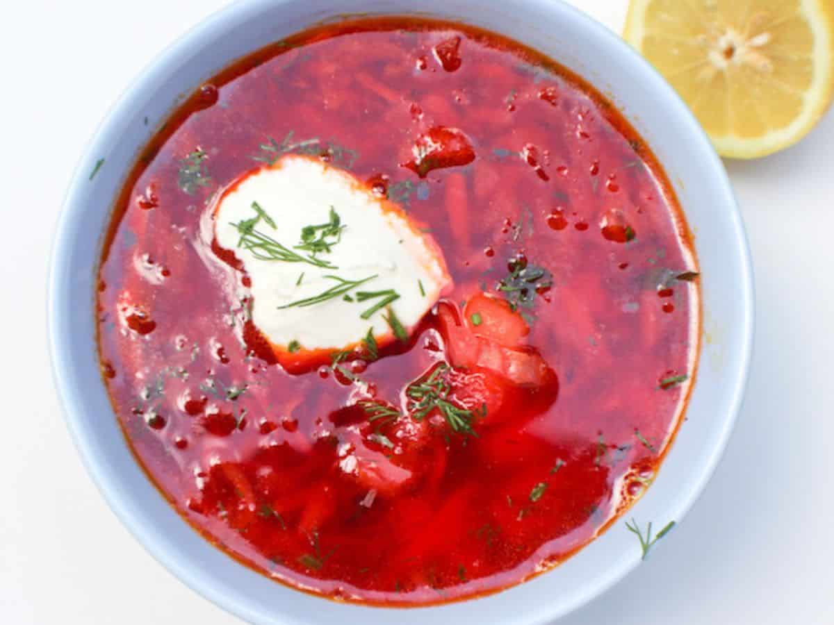 A bowl of red Ukrainian borscht served with dollop of sour cream. 