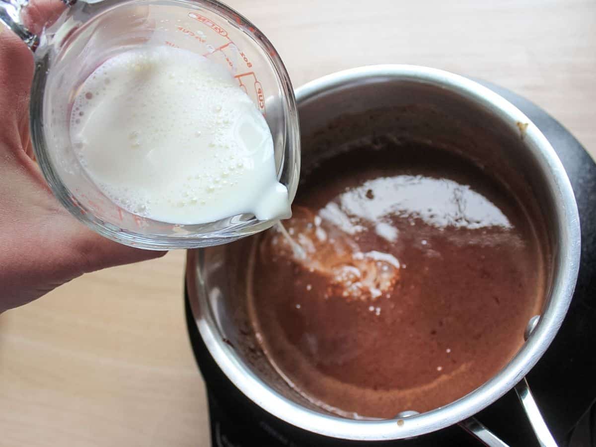 Adding corn starch and milk to the saucepan with chocolate.