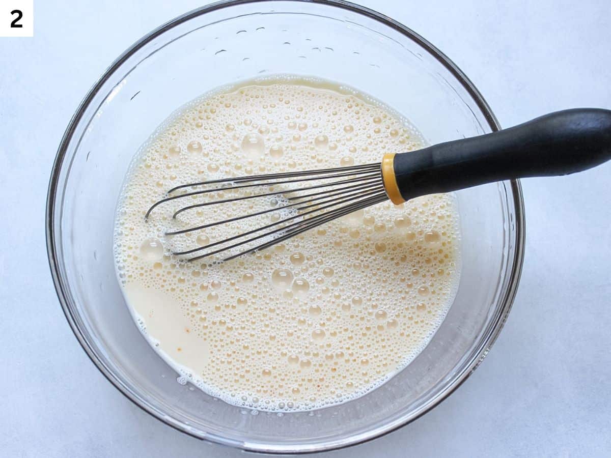 Whisking wet ingredients in a glass mixing bowl.