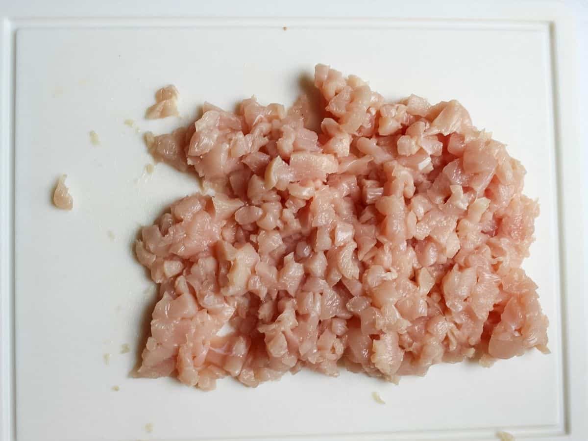 Diced chicken breasts on a cutting board for making chicken fritters.