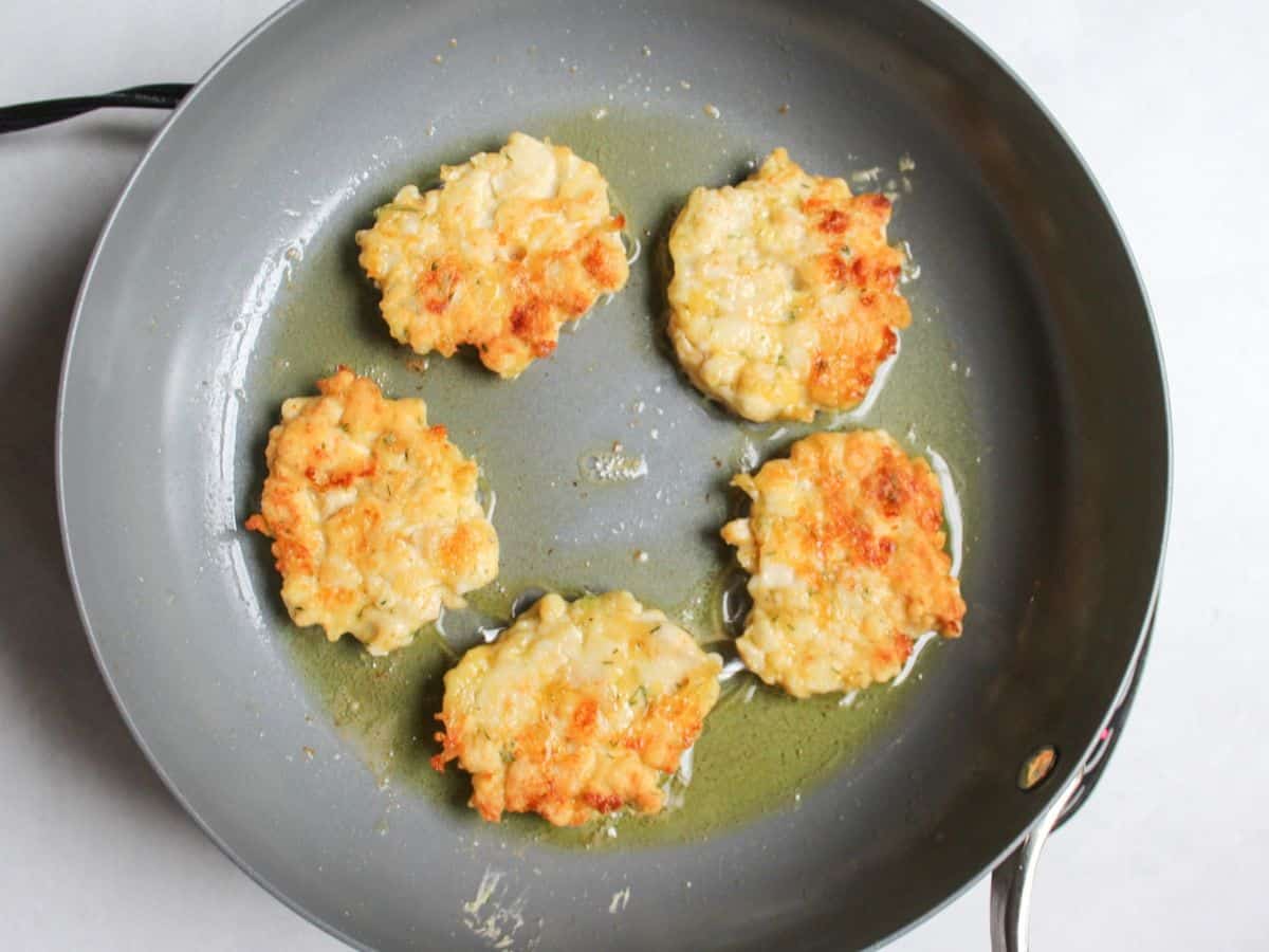 Frying chicken fritters in oil until golden in a skillet.