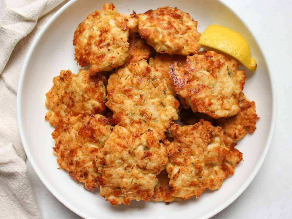 Golden chicken fritters made with diced chicken and cheese served on a plate.