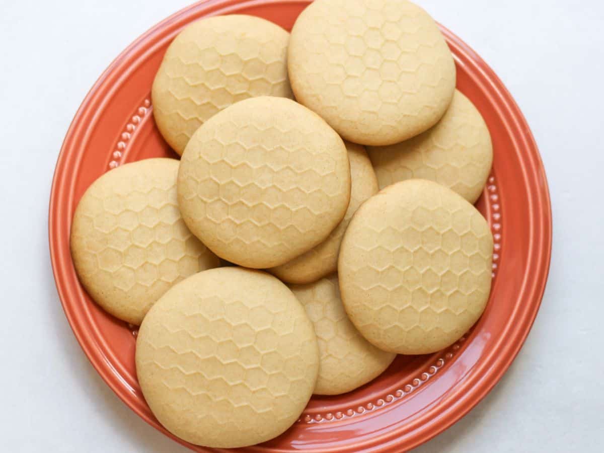 Honey sugar cookies with honey-comb tops piled up on a plate.